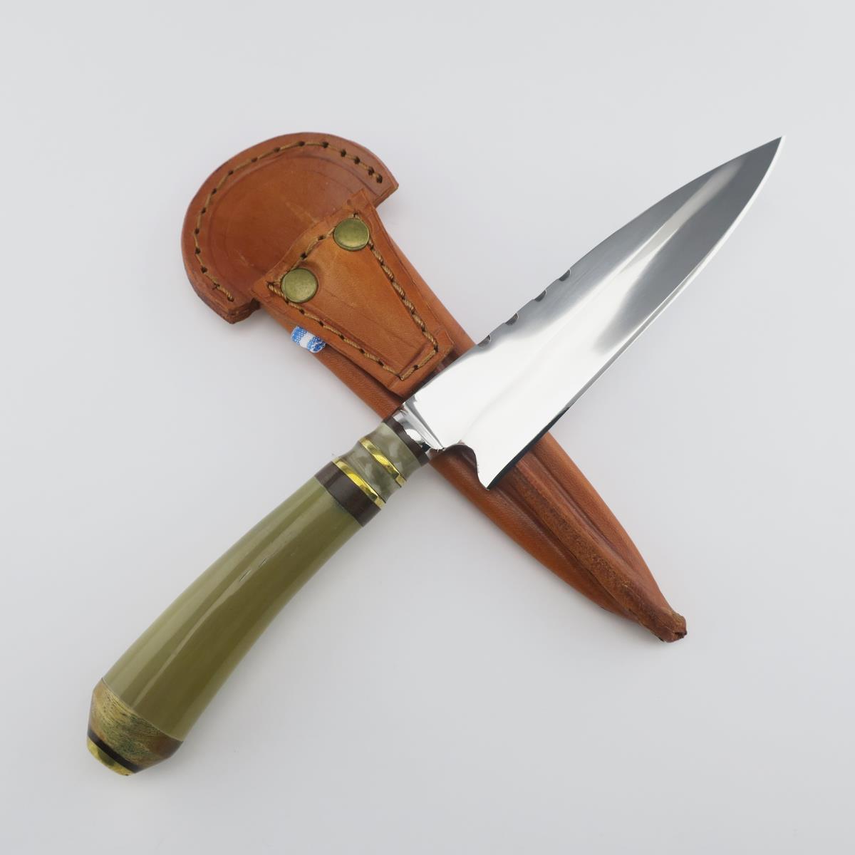 Cuchillo de acero inoxidable Cow 5.5in Light con hoja pulida y mango verde, apoyado sobre una funda de cuero color tostado con remaches de latón, sobre un fondo blanco limpio.