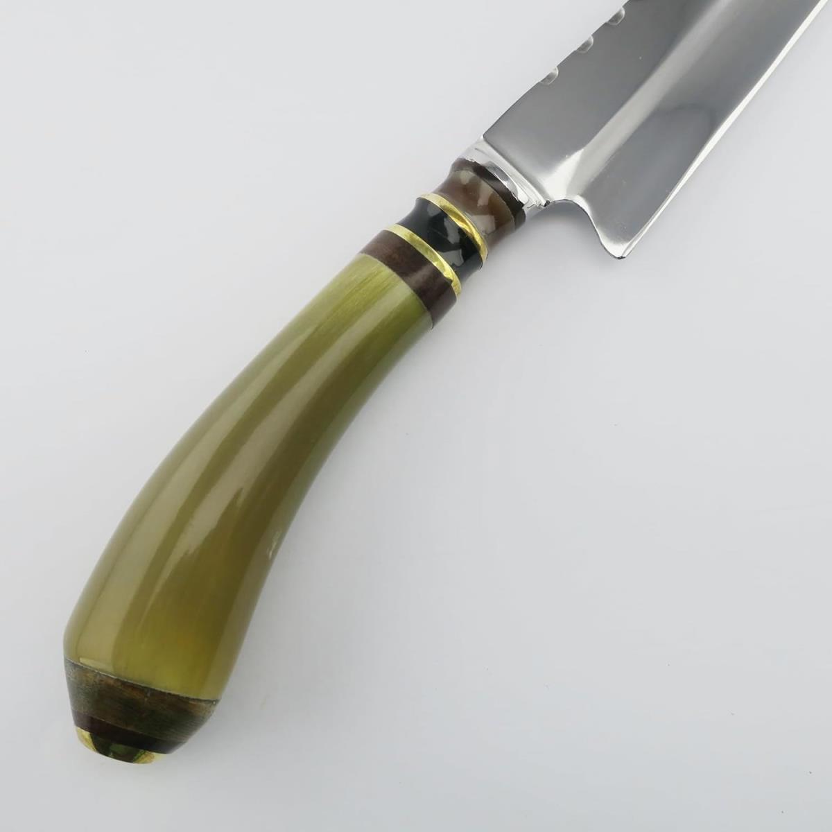 Un cuchillo Cow 6.3in Light con una hoja de acero inoxidable pulido y un diseño dentado distintivo, junto con un mango curvo verde oliva con detalles en negro, marrón y dorado, todo sobre un fondo blanco y liso.